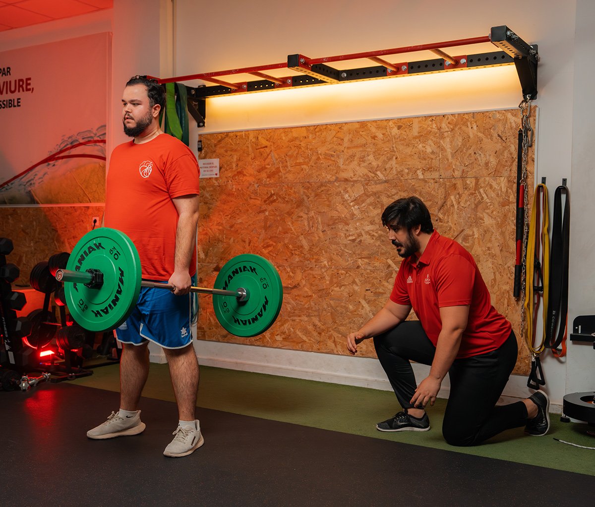 Entrenador personal supervisando técnica de ejercicio de fuerza con discos.