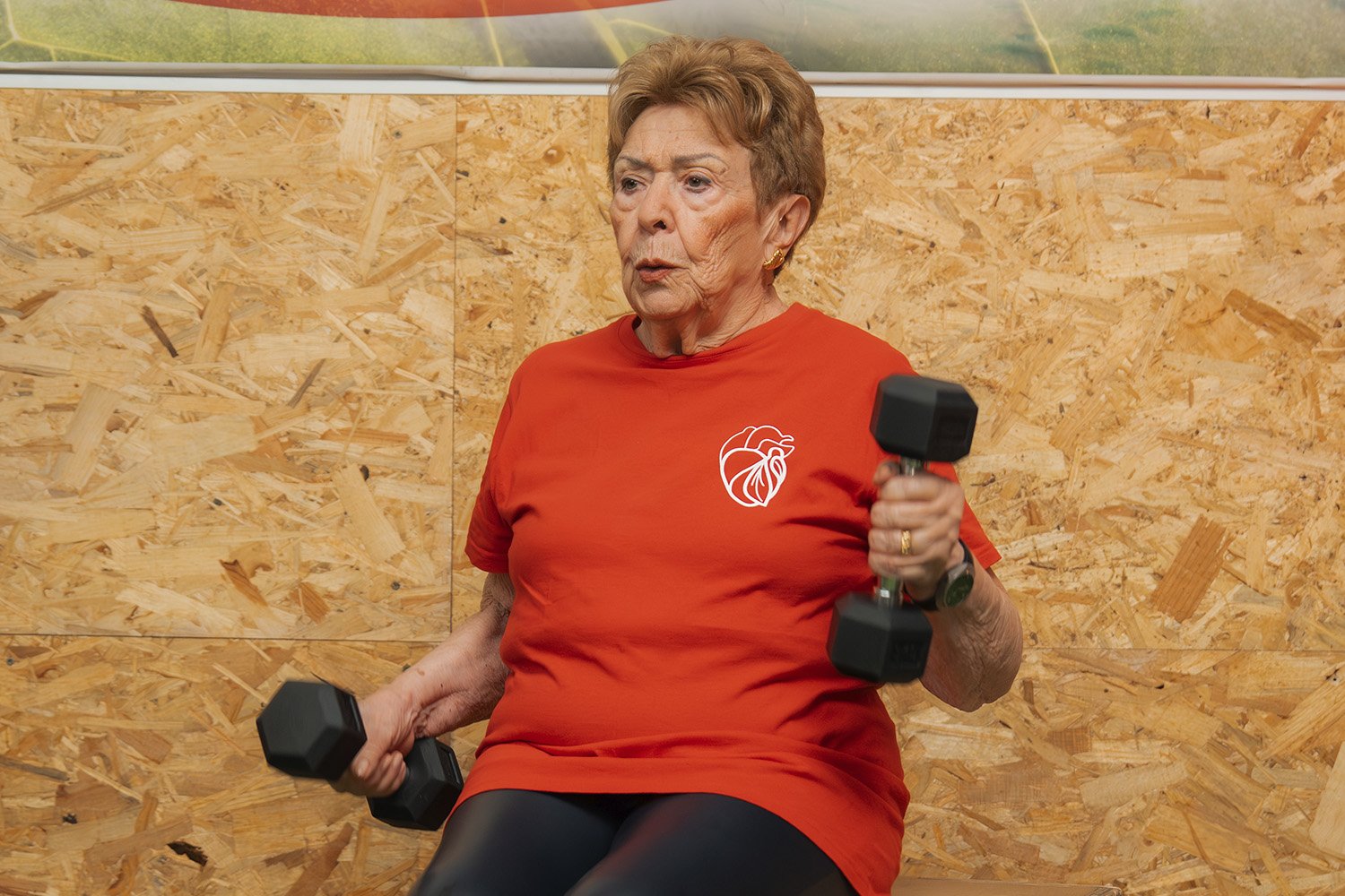 Mujer senior realizando ejercicios de fuerza sentada con mancuernas.